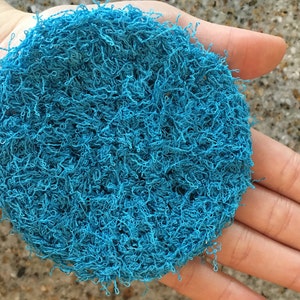 May include: A blue, round, textured scrubby made of tightly woven fibers.