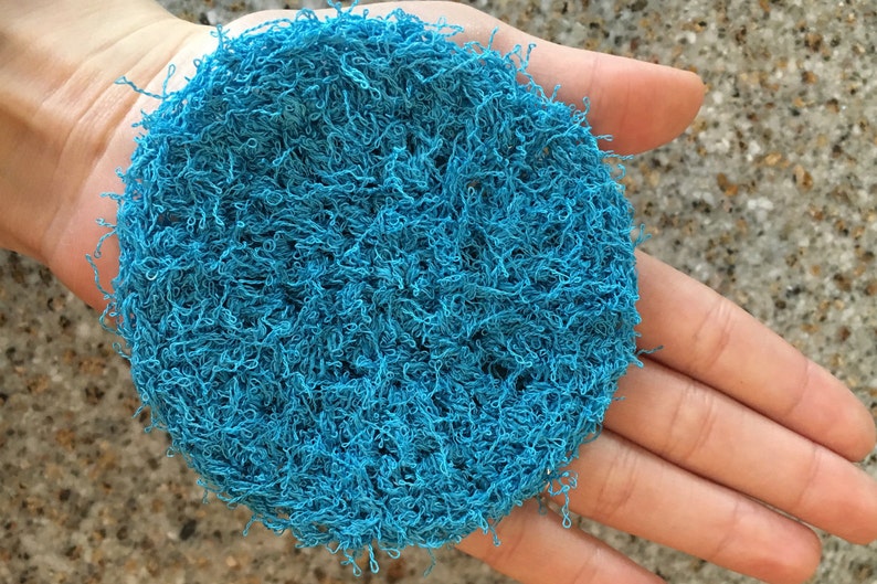 May include: A blue, round, textured scrubby made of tightly woven fibers.