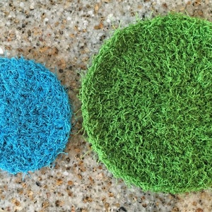 May include: Two round, crocheted scrubbers. One is blue and the other is green.