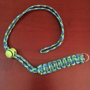 May include: A green, blue, and black paracord lanyard with a green plastic toggle and a silver metal ring.