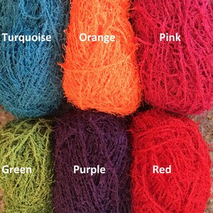 May include: Six skeins of yarn in different colors: turquoise, orange, pink, green, purple, and red. The yarn is a fuzzy, textured type.