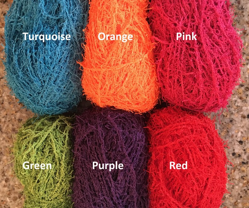 May include: Six skeins of yarn in different colors: turquoise, orange, pink, green, purple, and red. The yarn is a fuzzy, textured type.