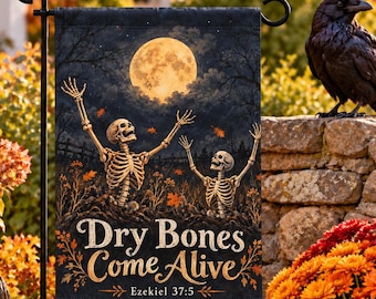 Puede incluir: Una bandera de jardín rectangular que muestra una escena nocturna oscura con luna llena, dos esqueletos emergiendo del suelo con los brazos levantados y el texto "Dry Bones Come Alive" seguido de "Ezekiel 37:5" en una fuente decorativa dorada.