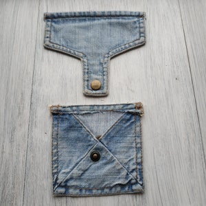 May include: Two denim pockets with a button closure. The top pocket is a simple rectangle shape, while the bottom pocket is a square shape with a diagonal seam.