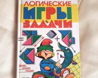 Puede incluir: Un libro antiguo titulado "Juegos y problemas lógicos" con texto e ilustraciones coloridas. La portada presenta un personaje de dibujos animados, formas geométricas y un pez. La portada del libro es blanca con un diseño amarillo, azul y rojo.