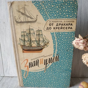 May include: A vintage book titled "От дракара до крейсера" (From the Drakkar to the Cruiser) with illustrations of ships. The book is part of the "Библиотечка пионера" (Pioneer Library) series and features a blue and white patterned cover with the text "Знай и умей" (Know and Be Able).