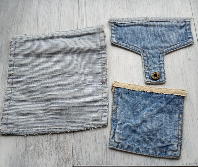 May include: Three denim patches, two are square and one is a rectangle with a rounded top. The rectangle has a button on the back.