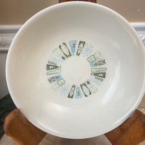 Op de afbeelding: Witte keramische kom met een geometrisch patroon in blauw, groen en zwart. Het patroon is een cirkel van abstracte vormen en sneeuwvlokken.
