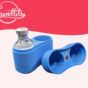 May include: A blue plastic container with two compartments, one holding a clear glass vial with a silver cap. The container is designed to hold and protect small vials.
