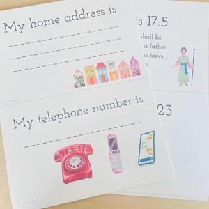 May include: Two white paper sheets with text and illustrations. One sheet reads "My home address is" with a row of colourful houses. The other sheet has "is 17:5" and a figure. The second sheet also has the text "My telephone number is" with images of phones.