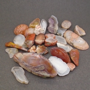 May include: A collection of agate stones in various shades of brown, white, and pink. The stones are smooth and polished, with intricate patterns and swirls.