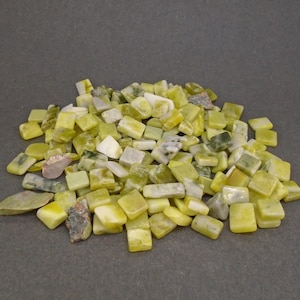 May include: A pile of small, rectangular, green and white jade stones. The stones are smooth and polished, and they have a variety of shapes and sizes.