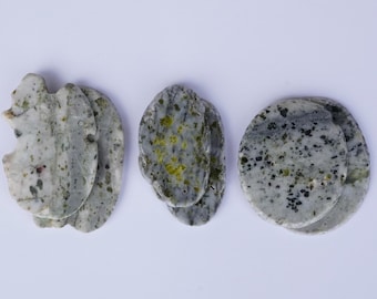 Puede incluir: Tres juegos de posavasos de piedra pulida con una base gris claro y patrones moteados en gris oscuro, negro y verde oliva. Los posavasos varían en forma, incluyendo formas orgánicas irregulares y un diseño circular con bordes suaves.
