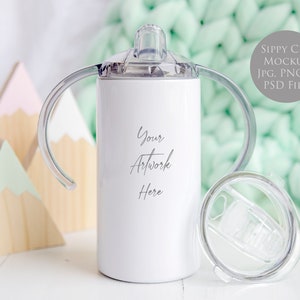 May include: White stainless steel sippy cup with two handles and a clear lid. The cup is on a white surface with wooden mountains in the background. The text "Your Artwork Here" is printed on the cup.