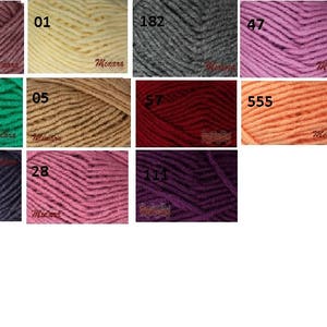 May include: A collection of yarn skeins in various colors, including shades of pink, green, gray, and orange. Each skein is labeled with a number, such as 278, 01, and 182. The yarn appears to be soft and suitable for knitting or crochet projects.