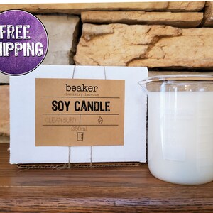 K&ouml;nnte beinhalten: Eine Sojakerze in einem becherf&ouml;rmigen Glasbeh&auml;lter, neben einer Schachtel mit der Aufschrift "Soy Candle" und "Clean Burn". Die Kerze ist mit wei&szlig;em Wachs gef&uuml;llt und hat ein Fassungsverm&ouml;gen von 260 ml.
