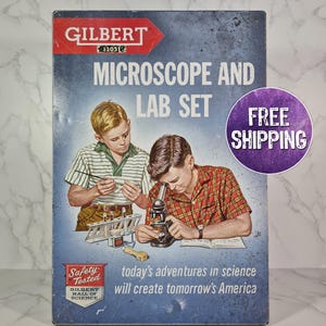 May include: Vintage Gilbert Microscope and Lab Set box. The box features illustrations of two boys conducting science experiments. Text includes "Microscope and Lab Set", "Safety Tested", and "today's adventures in science will create tomorrow's America".