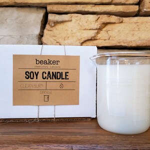 K&ouml;nnte beinhalten: Eine Sojakerze in einem becherf&ouml;rmigen Glasbeh&auml;lter. Die Kerze ist wei&szlig; und hat ein Fassungsverm&ouml;gen von 260 ml. Auf dem Etikett steht "beaker chemistry labware SOY CANDLE CLEAN BURN". Die Kerze ist in einer wei&szlig;en Pappschachtel verpackt.