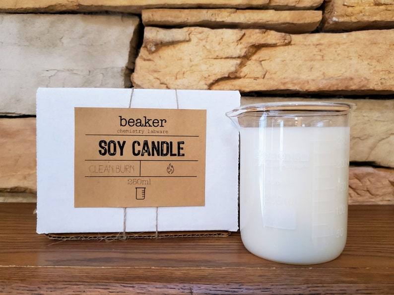 K&ouml;nnte beinhalten: Eine Sojakerze in einem becherf&ouml;rmigen Glasbeh&auml;lter. Die Kerze ist wei&szlig; und hat ein Fassungsverm&ouml;gen von 260 ml. Auf dem Etikett steht "beaker chemistry labware SOY CANDLE CLEAN BURN". Die Kerze ist in einer wei&szlig;en Pappschachtel verpackt.