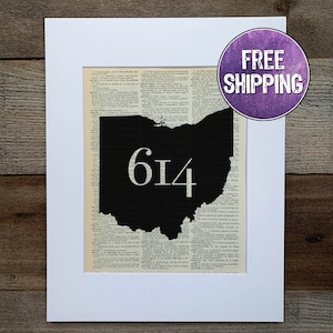 May include: A black and white print of the state of Ohio with the area code 614 printed in white on top of the state. The print is on a white background with a white mat.