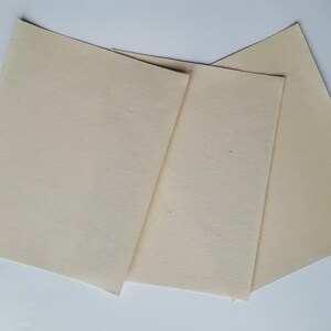 May include: Three off-white fabric squares, possibly for quilting or crafts.