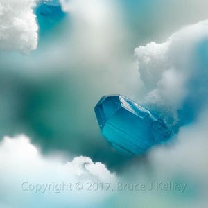 Könnte beinhalten: Ein großer, blauer Kristall liegt auf einer weißen, flauschigen Oberfläche. Der Kristall ist von einem weichen, blauen und weißen Hintergrund umgeben.