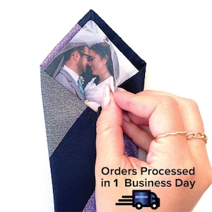 Peut inclure: Une cravate à motif bleu marine et violet avec une poche en plastique transparente qui contient une photo de mariage. Le texte "Commandes traitées en 1 jour ouvrable" est imprimé sous la photo. Une petite icône de camion avec le texte "21 RHINOS" est sous le texte.