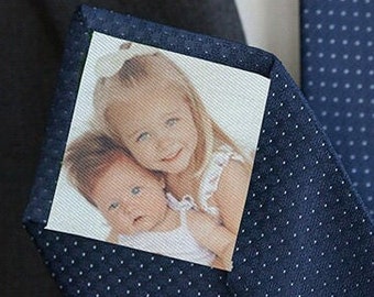 Puede incluir: Una corbata azul marino con lunares blancos, con un inserto de foto cuadrada de dos niños. La foto muestra a una niña pequeña sosteniendo a un bebé.