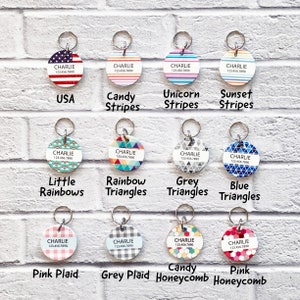 May include: Twelve different dog tag designs with the name "CHARLIE" and a phone number printed on each. The designs include USA flag, candy stripes, unicorn stripes, sunset stripes, little rainbows, rainbow triangles, grey triangles, blue triangles, pink plaid, grey plaid, candy honeycomb, and pink honeycomb.