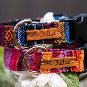 Op de afbeelding: Twee kleurrijke hondenhalsbanden met een zwarte gesp en ros&eacute;gouden D-ringen. De halsbanden hebben een geweven patroon en een bruin lederen label met de tekst "Chillbee" erop.