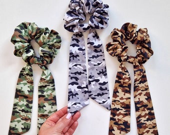 Camouflage scrunchie with long ribbon available in 3 colors: green, white, and brown. The ribbon is detachable. Hair tie scrunchie.