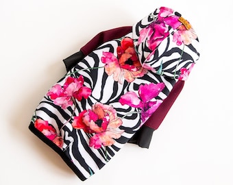 Könnte beinhalten: Ein schwarz-weißes Zebra-Kapuzenpullover mit einem floralen Muster in Rosa-, Rot- und Orangetönen. Der Pullover hat einen maroonfarbenen Ärmel.