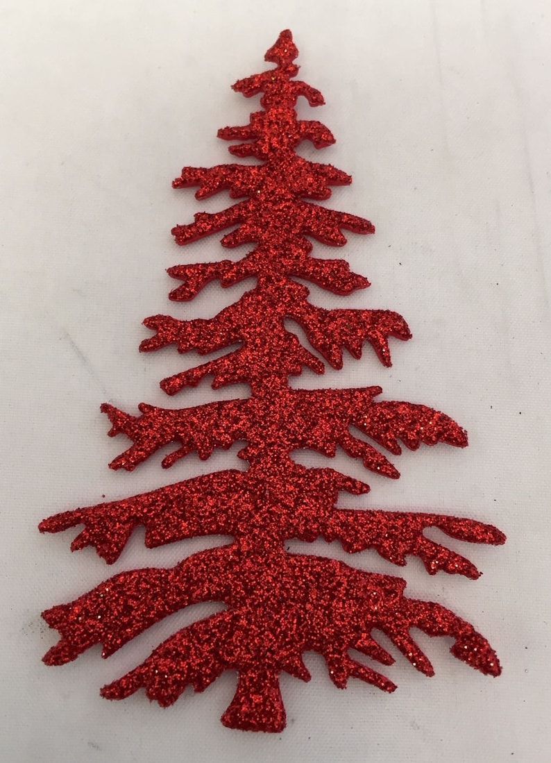 May include: A red glitter Christmas tree decoration. The tree is cut out in the shape of a fir tree with branches and a pointed top. The tree is covered in red glitter and is set against a white background.
