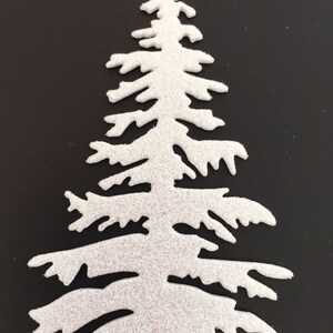 May include: A white, glitter-covered Christmas tree cutout. The tree has a classic evergreen shape with detailed branches. The glitter adds a sparkling effect, perfect for holiday crafts and decorations.