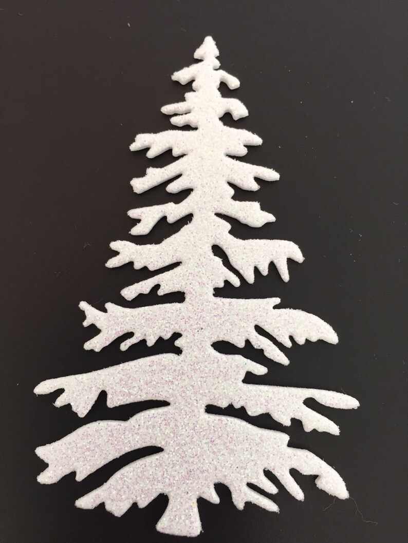 May include: A white, glitter-covered Christmas tree cutout. The tree has a classic evergreen shape with detailed branches. The glitter adds a sparkling effect, perfect for holiday crafts and decorations.