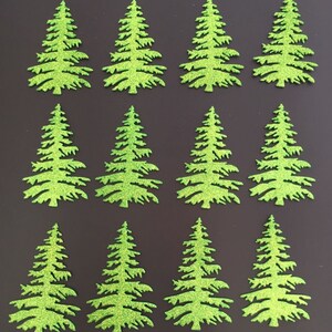 May include: Twelve glittery green Christmas tree cutouts arranged on a dark background. The trees are detailed with branches and a textured, sparkling finish. Ideal for holiday crafts and decorations.