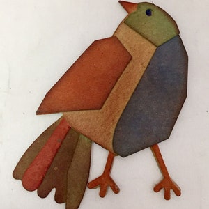 May include: A colorful, geometric bird cutout with a patchwork design. The bird features shades of brown, orange, green, and blue. It has small orange legs and a red beak. The bird is a decorative item, possibly for home decor or crafting.
