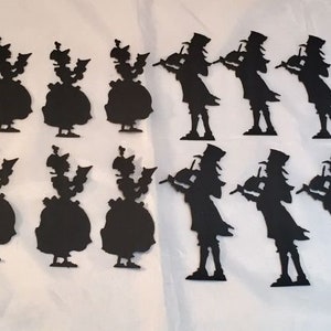 May include: Black silhouette cutouts of figures in two distinct designs. One design features a woman in a dress and hat, the other a man playing a violin, wearing a top hat and coat. The cutouts are arranged on a white surface.