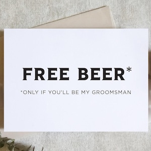 May include: A white card with the text "FREE BEER*" in bold black letters. Below, smaller text reads "*ONLY IF YOU'LL BE MY GROOMSMAN". The card is on a neutral background with decorative elements.
