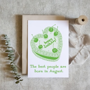 May include: A green birthday card with a heart-shaped cake and the text "Happy Birthday!" and "The best people are born in August."