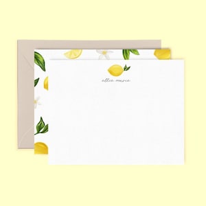 May include: Stationery set featuring a white notepad with a watercolor lemon design and the text "ellie marie". The notepad is accompanied by a matching envelope with a light brown color.
