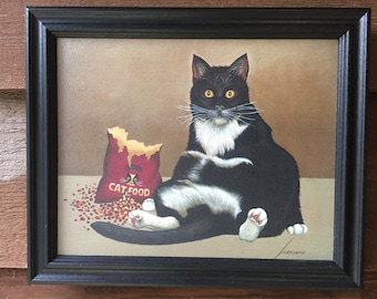 May include: A black and white cat with a white chest and paws sits in front of a bag of cat food. The bag is red with a white cat face and the words "Cat Food".