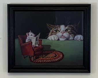 Whimisical cat and mouse wall decor framed in a wood black frame that features a curious cat watching a mouse relaxing in a armchair.