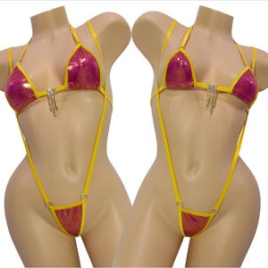 May include: A two-piece swimsuit with a halter top and thong bottom. The swimsuit features a pink and yellow color scheme with rhinestone accents. The top and bottom are connected by yellow straps.