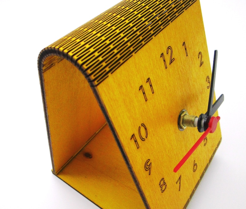 May include: A wooden clock with a yellow finish and black numbers. The clock has a red second hand and black hour and minute hands. The clock is on a white background.