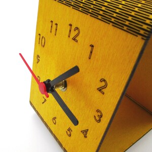 May include: A yellow wooden clock with black numbers and hands. The clock has a red second hand and is set to 10:10.