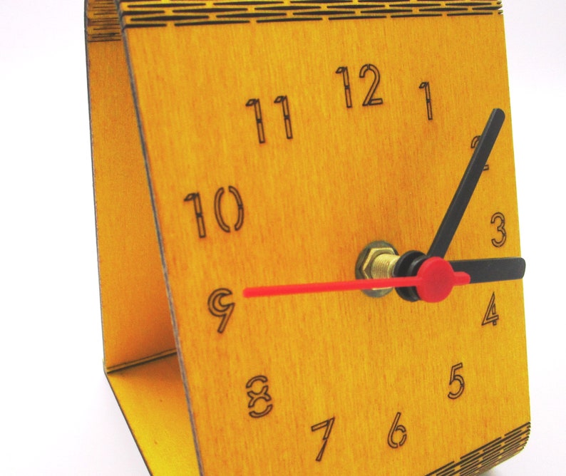May include: A wooden clock with black and red hands. The clock face is yellow and has black numbers 1 through 12.