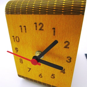 May include: A wooden clock with black numbers and hands. The clock face is yellow and the hands are black and red.