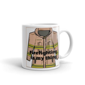 May include: White ceramic mug featuring a tan firefighter jacket illustration with yellow stripes and the text "Firefighting is my thing." The mug has a standard handle and a simple design.