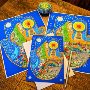 May include: Two blue and yellow Hamsa hand cards with the word "Israel" and "Shema" on them. The cards are decorated with colorful illustrations of Jerusalem and the Western Wall.